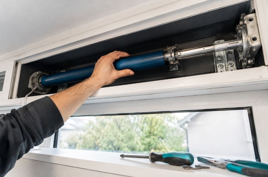 Técnico ajustando el motor tubular de una persiana desde el interior de una vivienda